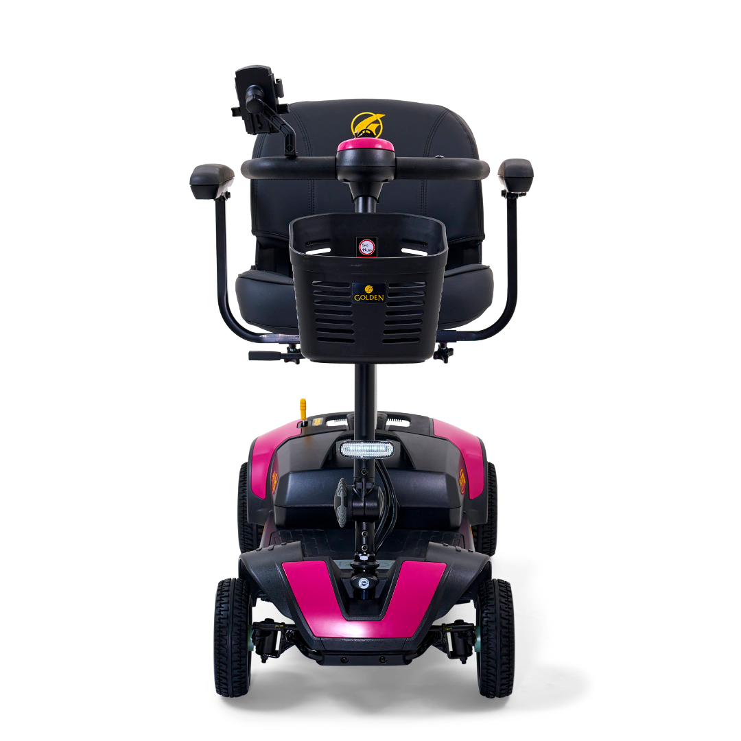 The front view of the Golden Tech GB124 Buzzaround XL 4-Wheel Portable Mobility Scooter showcases a pink and black design, extended range battery, cushioned black seat with armrests, a control tiller, and four wheels for enhanced maneuverability.