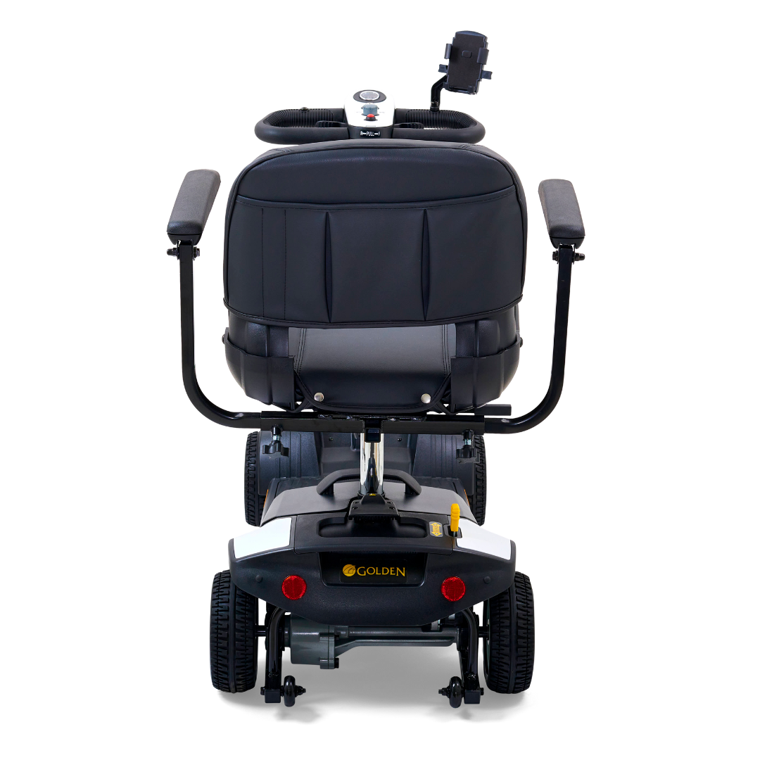 Rear view of a Golden Tech GB124 Buzzaround XL 4-Wheel Portable Mobility Scooter with a black cushioned seat, armrests, and control panel. It includes an extended range battery and a small rear luggage rack for added convenience on all trips.