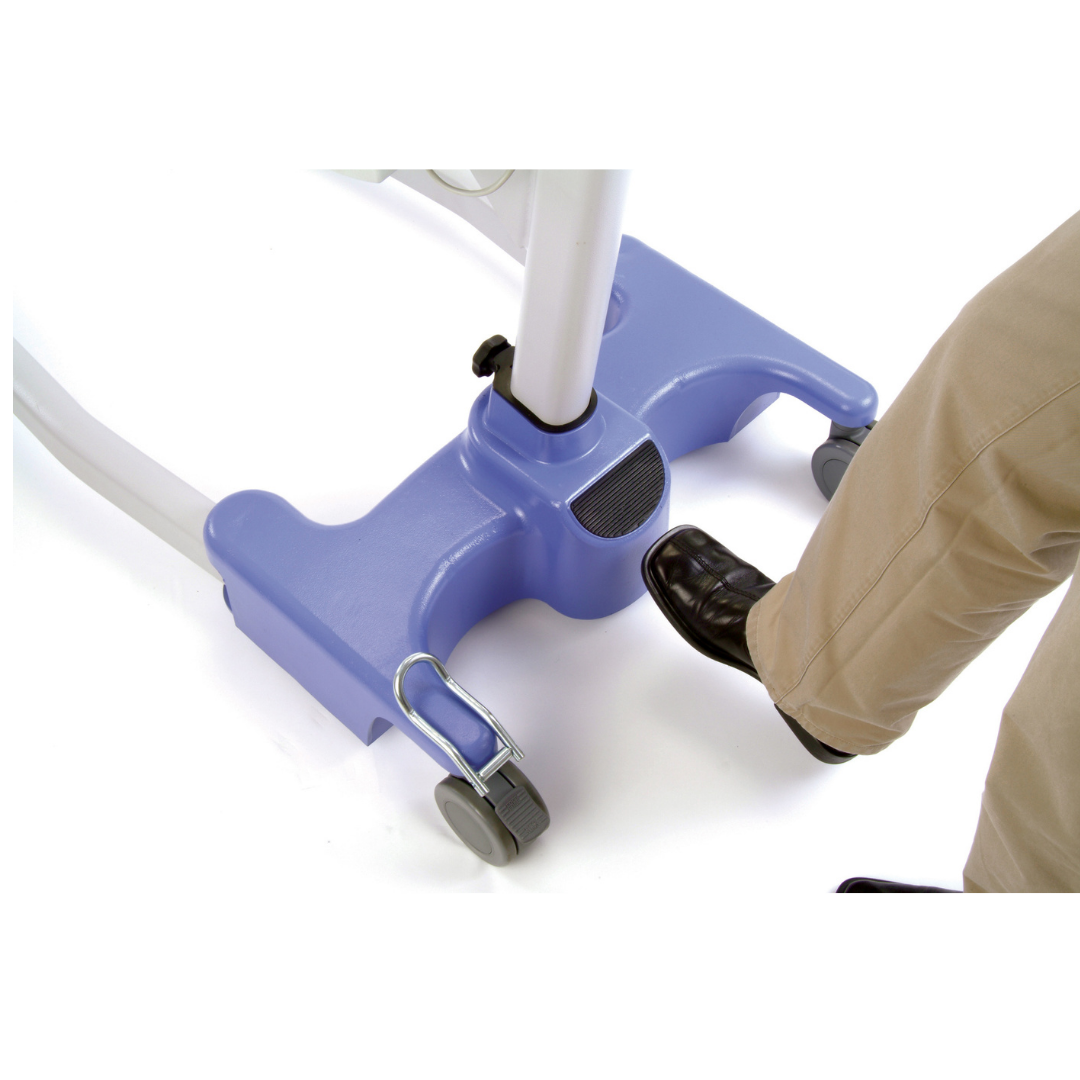 A person in beige pants and black shoes presses a foot pedal on the blue and white Joerns Hoyer Journey® Sit-To-Stand Folding Electric Patient Lift, designed to enhance caregiver efficiency in patient mobility.