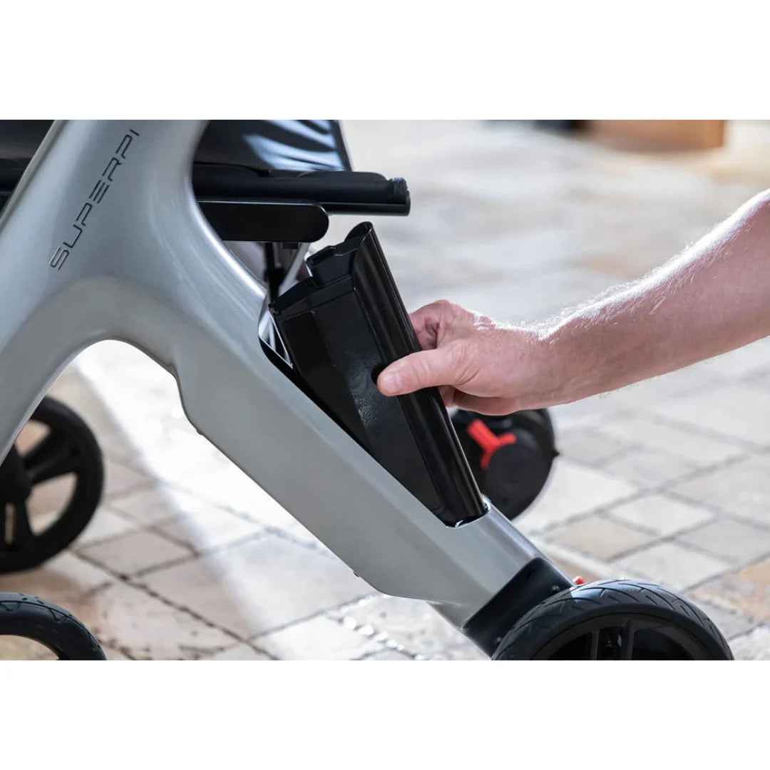 A hand inserting a black rectangular Extra Battery for SuperPi W1 into the frame of a mobility device.