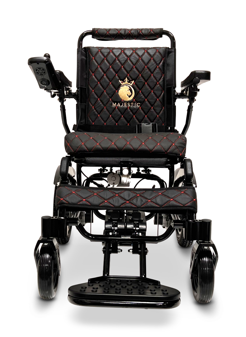The ComfyGo MAJESTIC IQ-9000 Auto Reclining Electric Wheelchair features a black quilted seat and backrest with red stitching, aircraft-grade aluminum alloy frame, armrest controls, and a gold Majestic crown logo on the backrest.