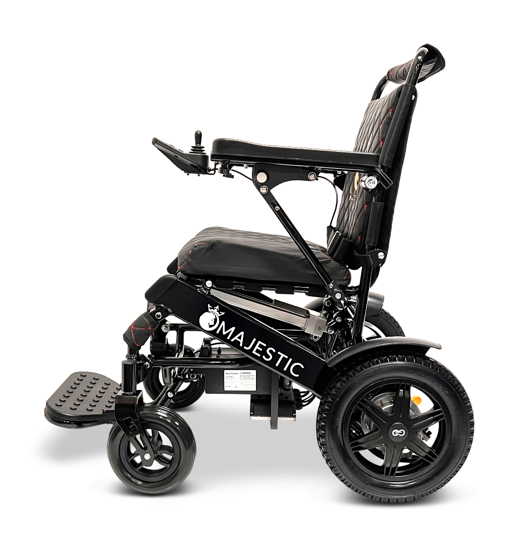 A side view of the black ComfyGo MAJESTIC IQ-9000 Auto Reclining Electric Wheelchair, made from aircraft-grade aluminum alloy, with large rear wheels, padded seat, raised footrest, and “Majestic” branding on the side against a plain background.