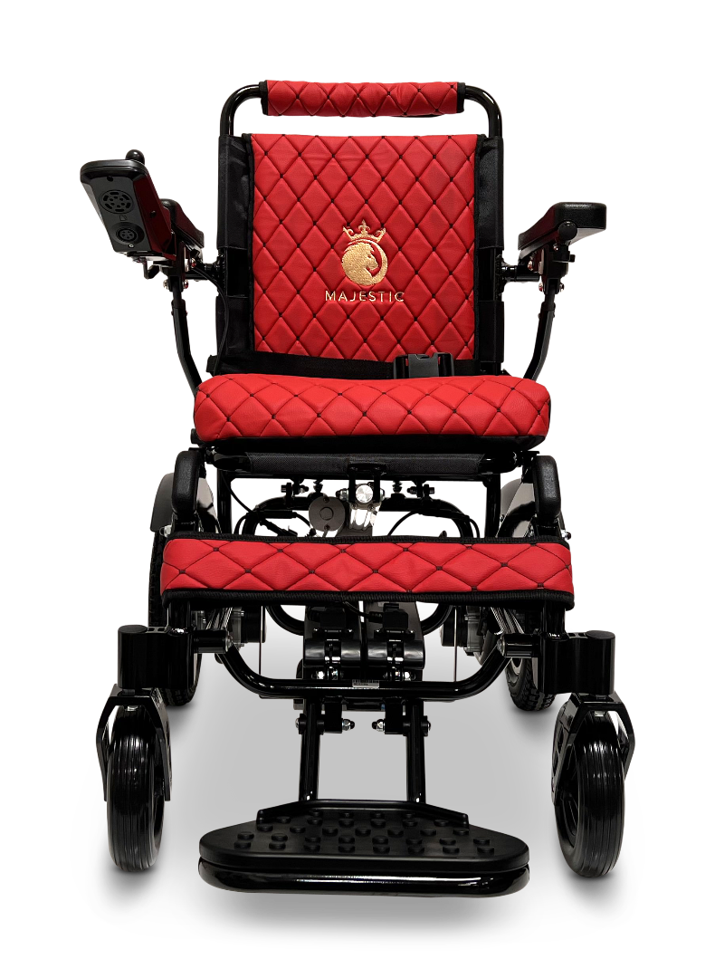 A front view of the ComfyGo MAJESTIC IQ-9000 Auto Reclining Electric Wheelchair in red and black, featuring quilted upholstery, armrests, a left-side digital joystick controller, and Majestic branding with a gold horse logo on the backrest.