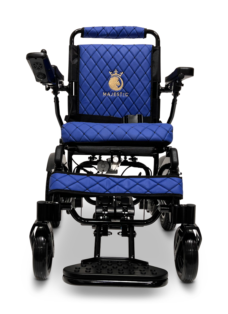Front view of the ComfyGo MAJESTIC IQ-9000 Auto Reclining Electric Wheelchair, featuring aircraft-grade aluminum alloy, blue quilted cushions, armrests, footrest, left-side control panel, and a “Majestic” logo with crown on the backrest.