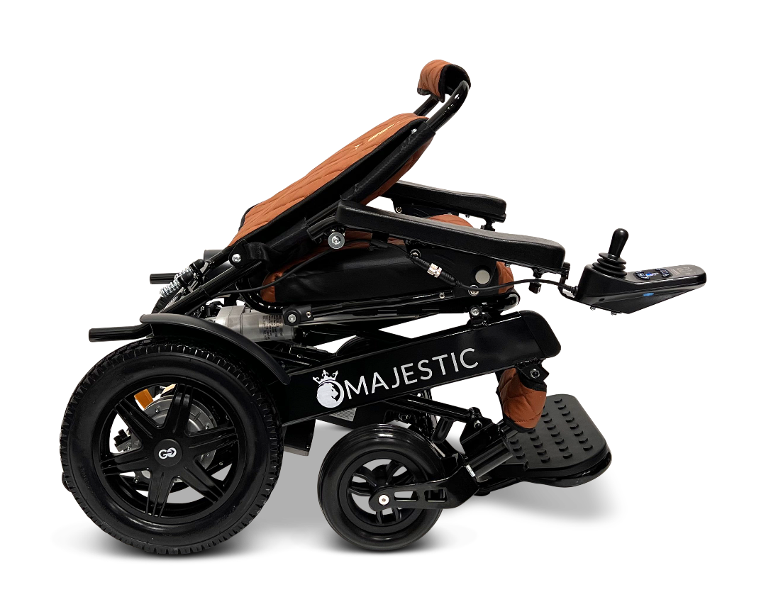 A black ComfyGo MAJESTIC IQ-9000 Auto Folding Electric Wheelchair featuring large rear wheels and a brown cushioned seat, shown from the side. Equipped with a digital joystick controller on the right armrest, this model is powered by brushless silent motors and includes front footrests to ensure optimal comfort.
