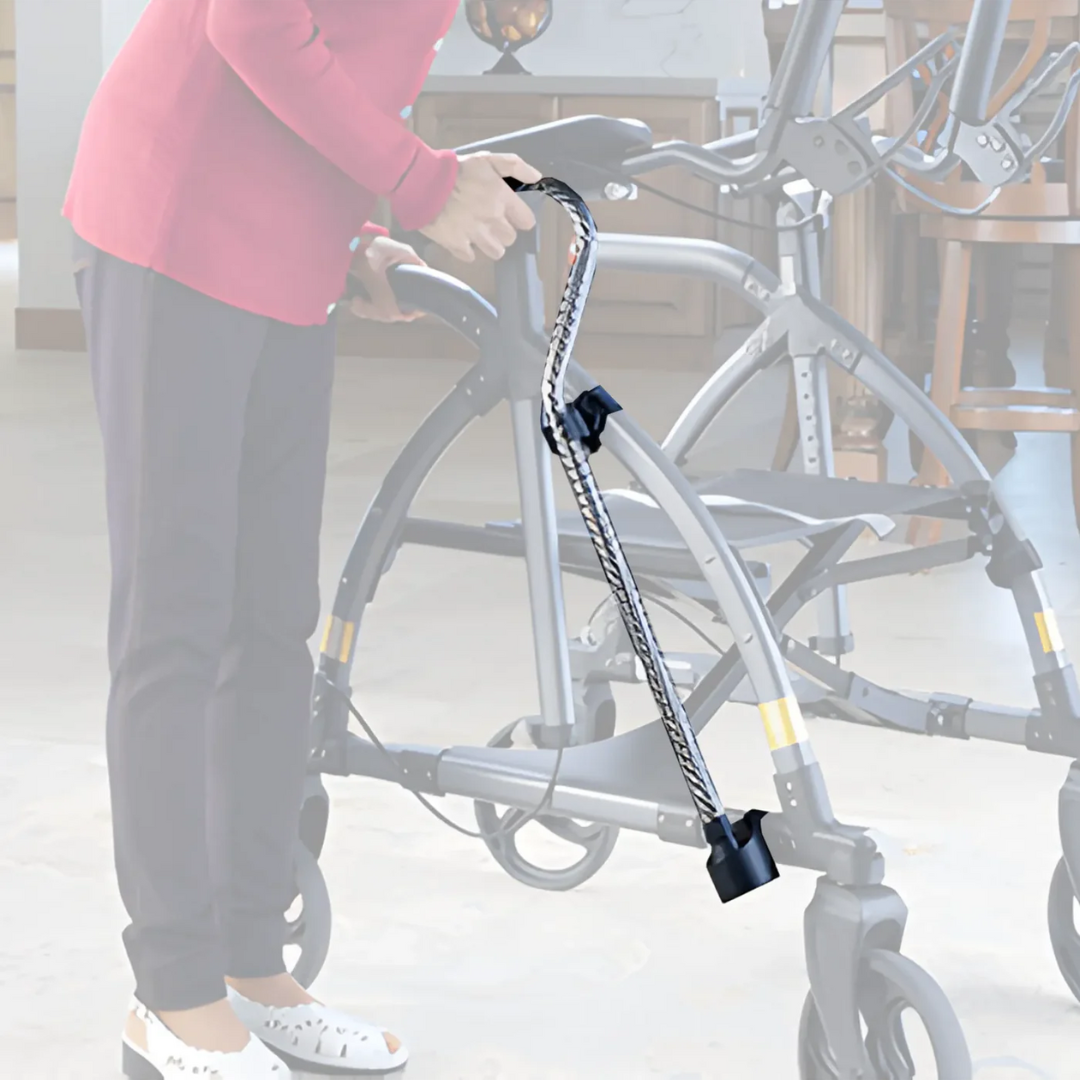 Indoors, a person in a red shirt and dark pants places a black and white walking cane onto a gray walker with wheels. The focus is on mobility assistance items, enhanced by Journey UPWalker Parts & Accessories for added ease.