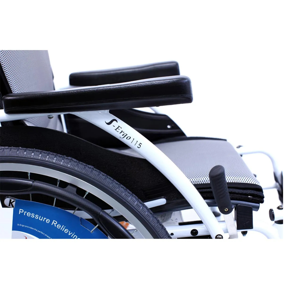 A close-up of the Karman S-Ergo 115 Ultra Lightweight Wheelchair reveals its ergonomic seating with cushioned seat and armrest. Visible are parts of the wheel, a pressure-relieving sticker on the wheel cover, and its white frame with black accents.