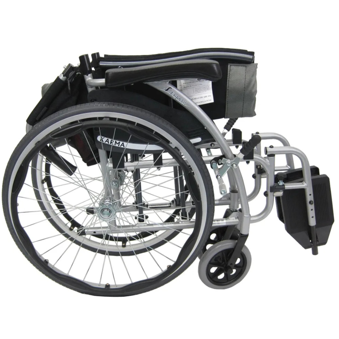The Karman S-Ergo 115 Ultra Lightweight Ergonomic Wheelchair, weighing only 25 lbs, features a foldable metal frame with a black seat, large rear wheels, small front wheels, and upward-folding footrests. Its compact design ensures portability and ergonomic seating for enhanced comfort.