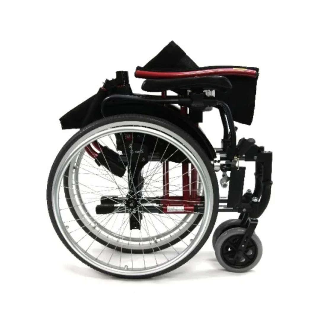The folded Karman S-Ergo 305 Ultra Lightweight Ergonomic Wheelchair, viewed from the side, showcases silver wheels and a black frame with red accents. Its compact design enhances portability and storage, with small front wheels indicating its crafted for manual use and long-term mobility.