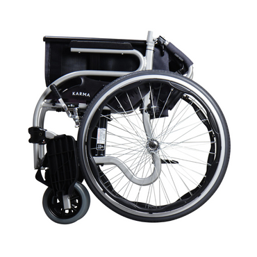 The Karman Healthcare STAR 2 Lightweight Folding Wheelchair is shown folded for storage or transport, featuring a silver frame, large rear wheels, smaller front wheels, and the Karman brand name on the fabric seat.