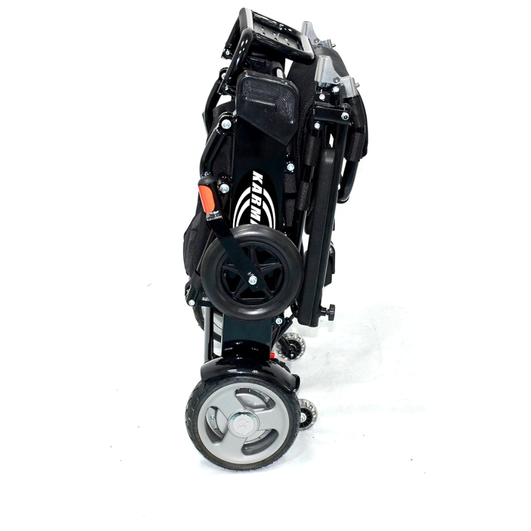 The Karman Tranzit Foldable Lightweight Power Wheelchair, FAA approved, is a sleek, compact mobility device with two large wheels, handlebars, and a seat. Its black frame is enhanced with metal parts and orange highlights against a white background.