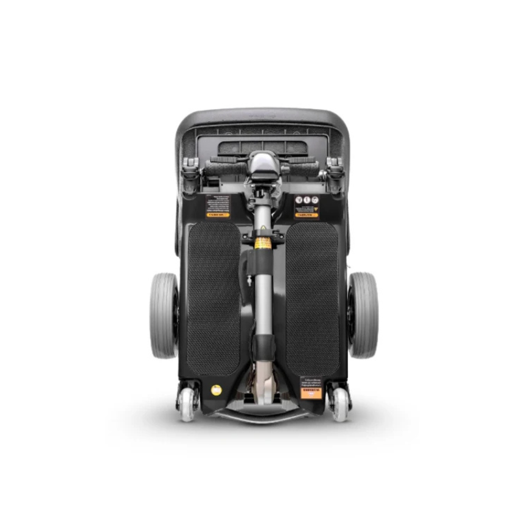 Top-down view of a folded FreeRider Luggie Elite Travel Scooter, highlighting its wheels, footrests, and frame labels. The image emphasizes the scooter’s compact, foldable, and portable design.