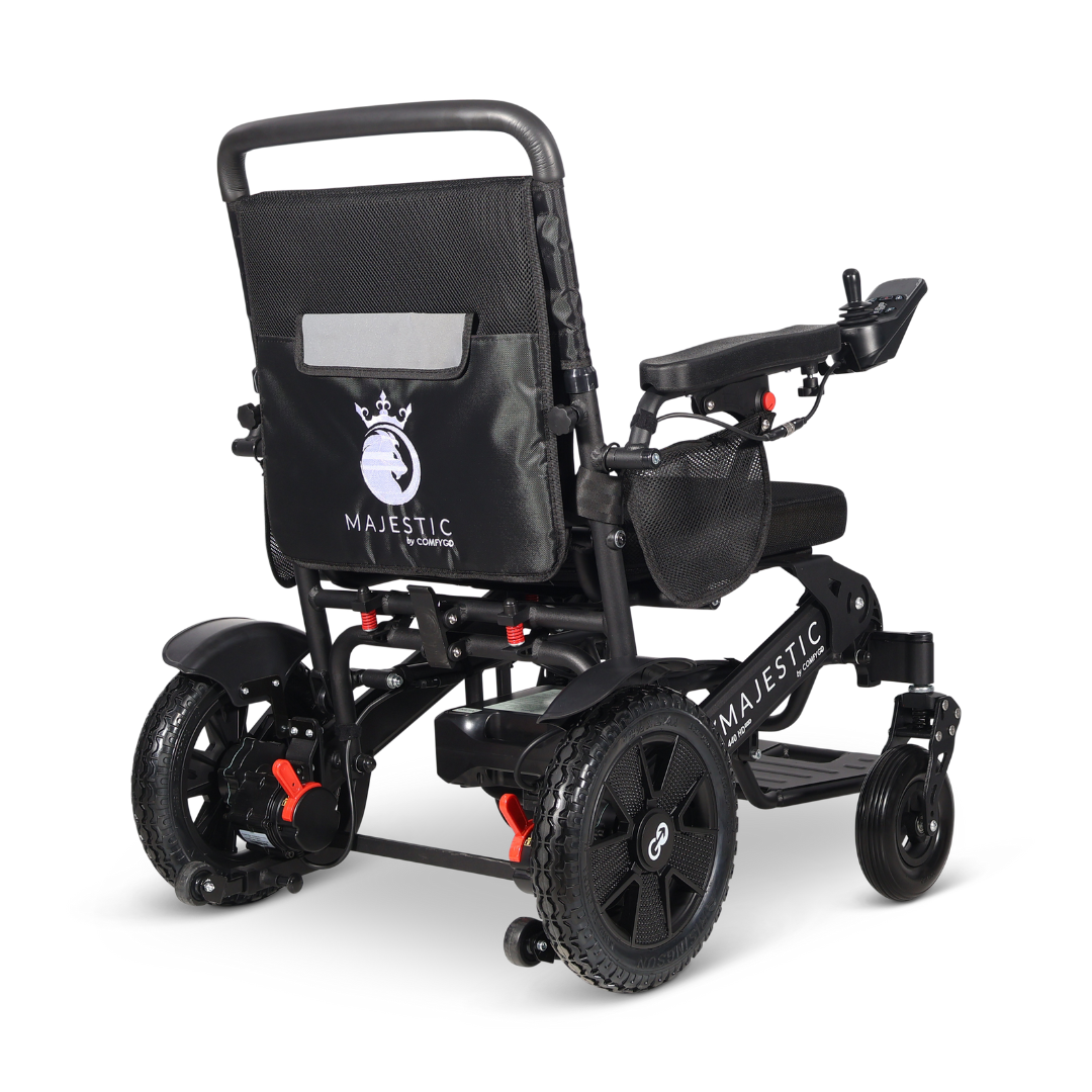 The ComfyGo Majestic 440 HD PLUS Bariatric Portable Powerchair is a black heavy-duty electric wheelchair with a padded seat, armrest joystick, sturdy rear wheels, rear storage pouch with the Majestic logo, shown from a rear angle.