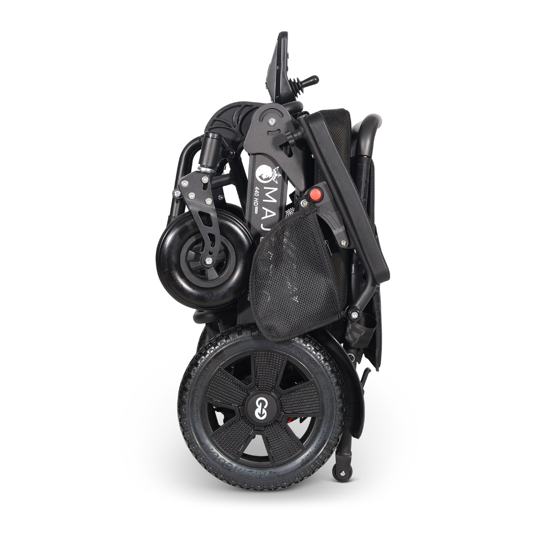 The ComfyGo Majestic 440 HD PLUS Bariatric Portable Powerchair is shown folded compactly in black, with its wheels and frame secured upright for easy storage or transport, highlighting its travel-approved, portable design.
