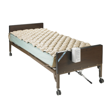 A hospital bed with metal rails, dark wood-style head and footboards, wheels, and a side lever. Features the Drive Med-Aire Alternating Pressure Pump and Pad System with a beige air mattress for comfort and pressure relief.