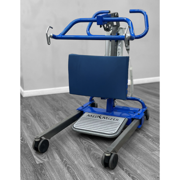A Med-Mizer Flex Medriser Sit-To-Stand Electric Patient Lift in blue and gray, featuring wheels, a padded backrest, and handles, is placed on a wood-patterned floor beside a light-colored wall.