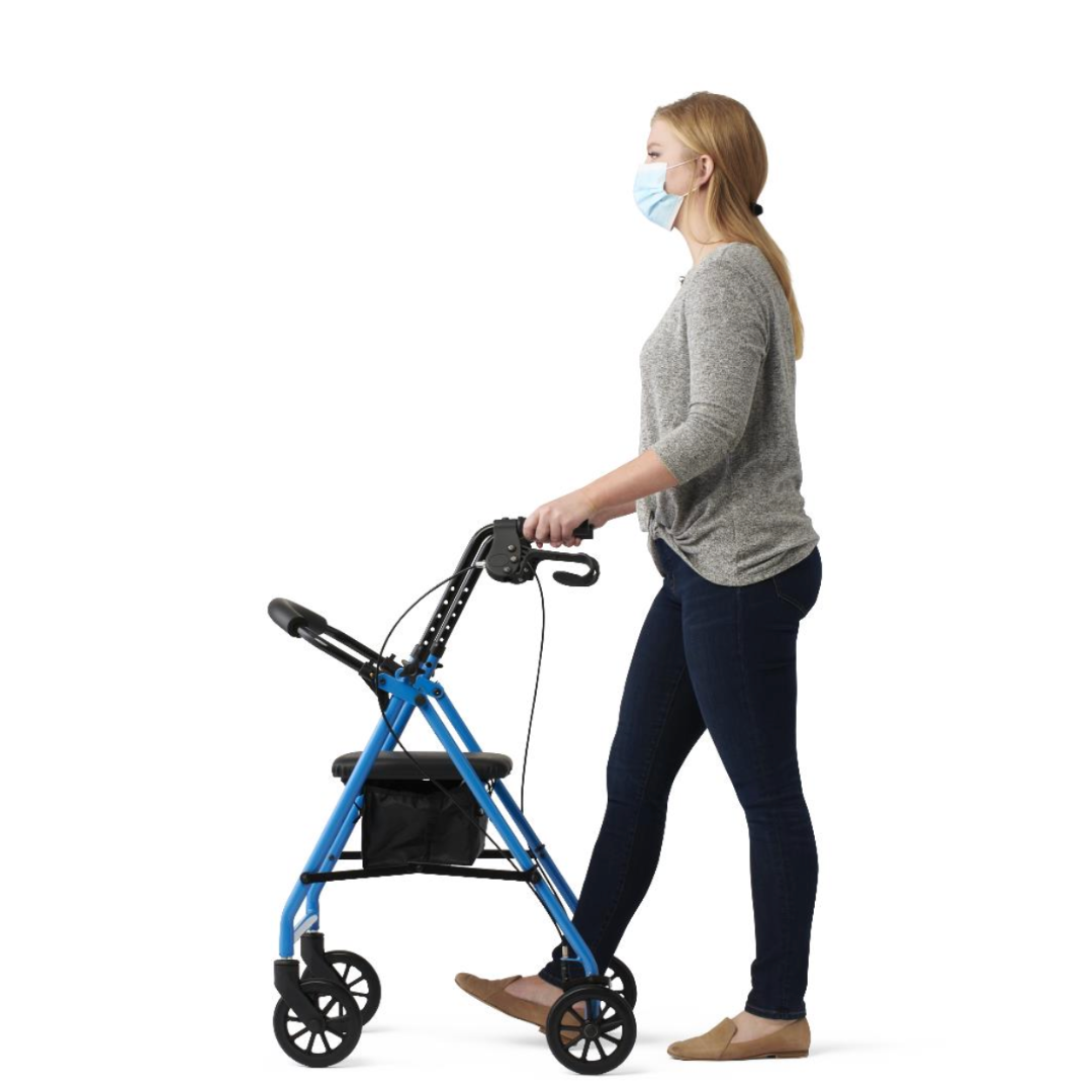 A casually dressed person wearing a mask pushes a Medline Basic Lightweight Steel Folding Rollator, blue in color with a small black storage bag, against a white background.