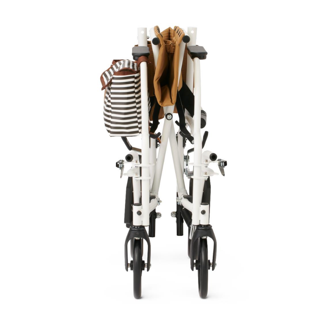 A folded Medline Designer High-Performance Transport Chair with a durable steel frame is viewed from the back, featuring a brown item and a striped black-and-white bag on the handles, standing upright on its black wheels.