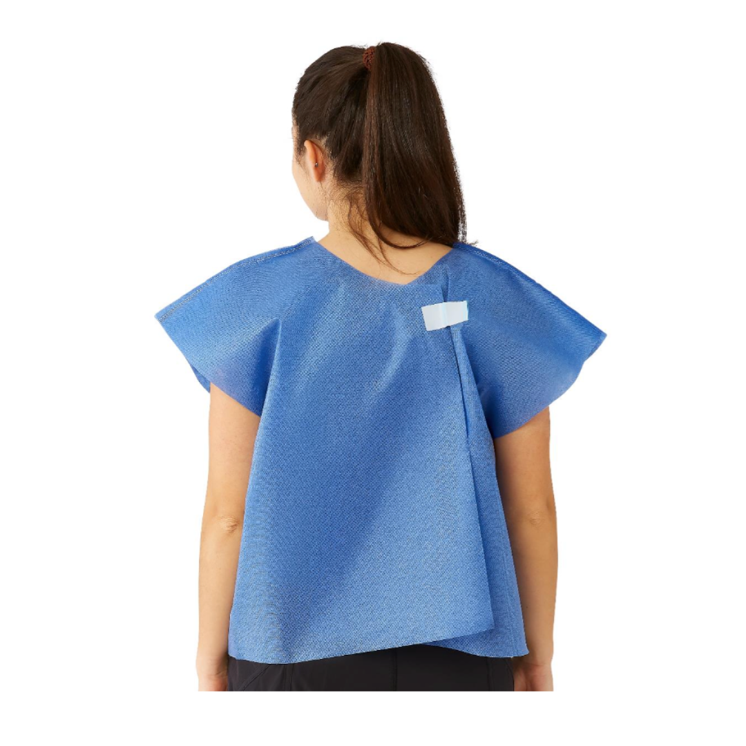 A woman with a ponytail is seen from behind wearing a Medline Disposable Multilayer Patient Cape, 30" x 21", blue, with a white velcro fastener at the upper back and short sleeves for added comfort.