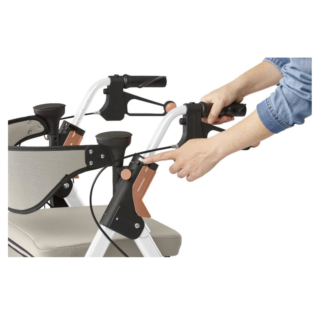 A person in a denim shirt demonstrates pressing the brake levers on a Medline Empower Rollator with Microban, highlighting the handle and braking mechanism for optimal mobility assistance with its advanced design and durable aluminum frame.