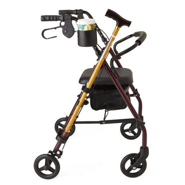 A red mobility walker with four wheels and a cushioned seat, featuring a black storage bag, Medline Cup and Cane Holder Combo Pack for Walker/Rollators with a white-green cup, and an attached wooden cane carrier.