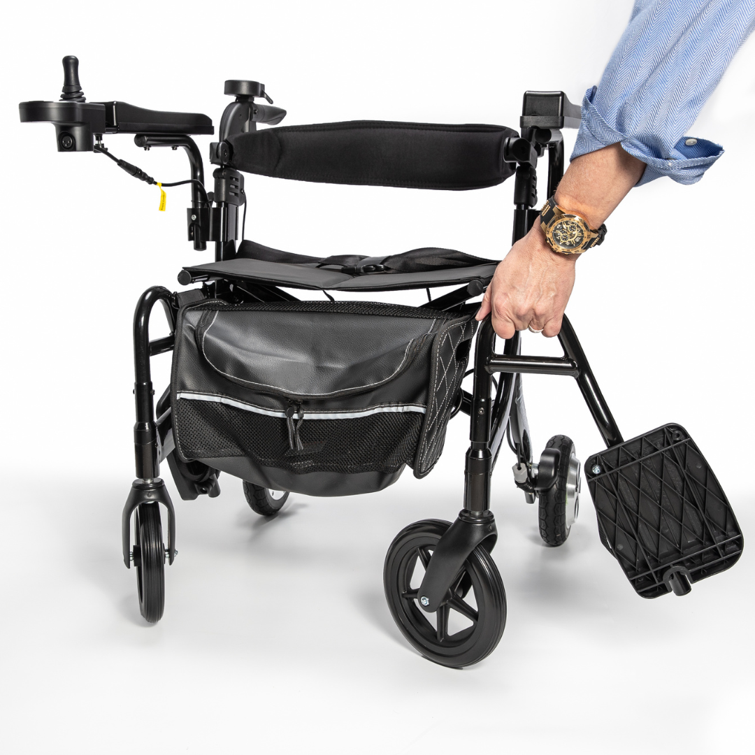 A person’s hand holds the Miracle Mobility Portable 4N1 Walker Wheelchair Combo, a lightweight travel-ready mobility aid with a black storage bag attached to the front, displayed against a white background.