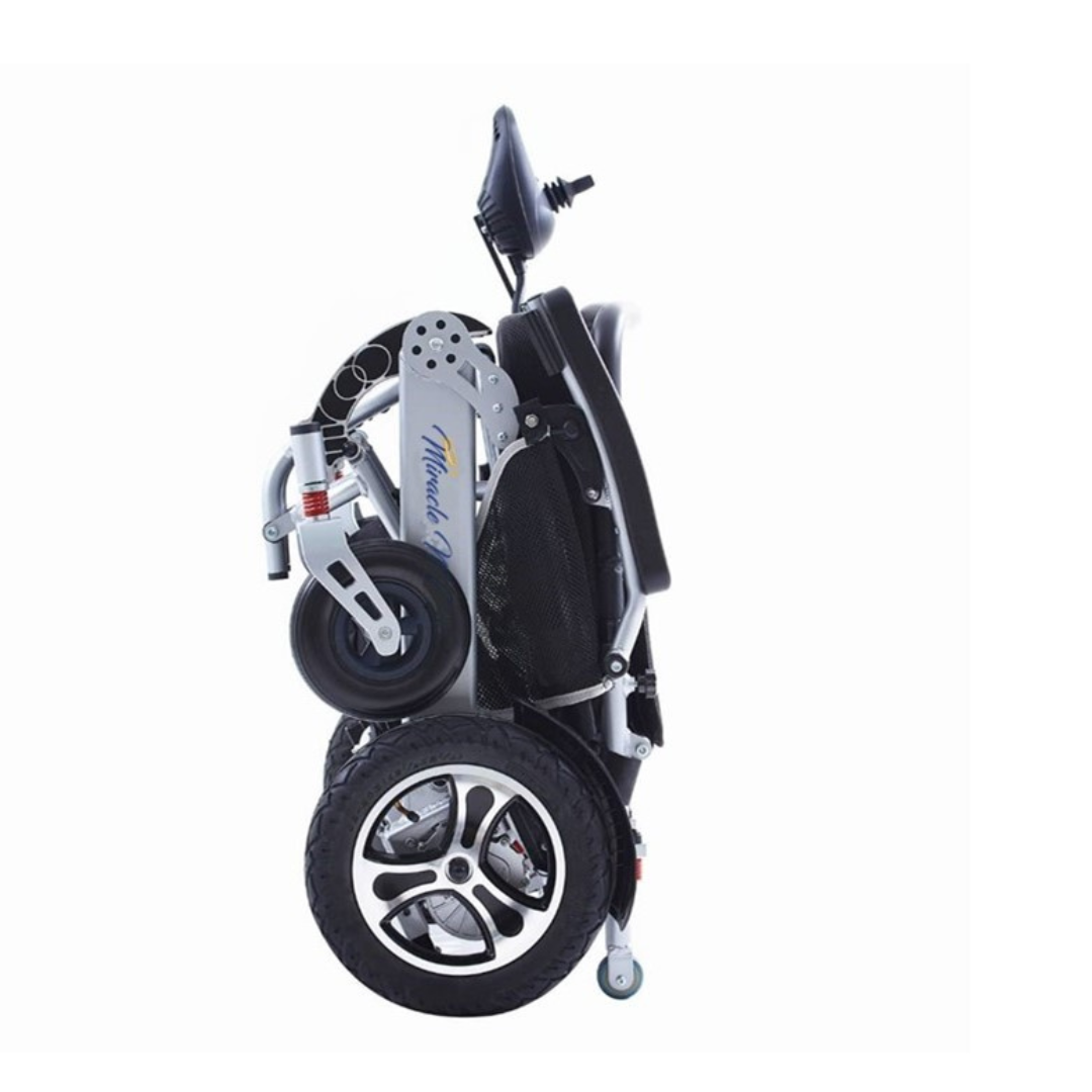 The Miracle Mobility Platinum 8000 Bariatric Portable Powerchair stands upright on its wheels, highlighting its lightweight, portable metallic frame design against a white background.