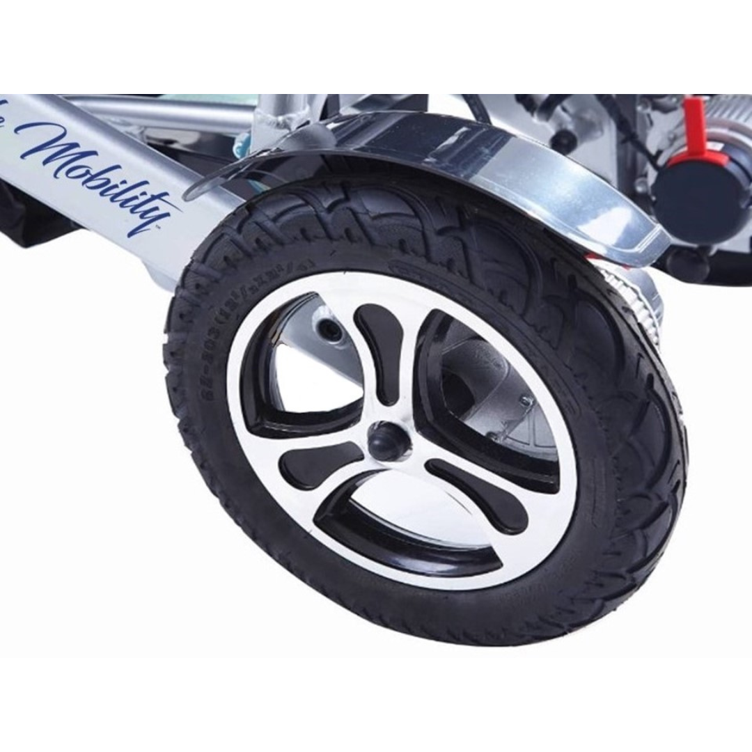 Close-up of a black and silver wheel with thick tread, attached to a metal frame—part of the Miracle Mobility Platinum 8000 Portable Powerchair - Open Box. The word "Mobility" is partially visible on the frame.