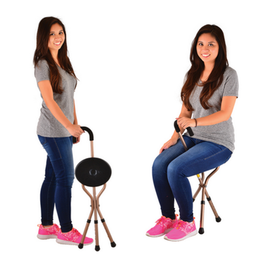 A woman demonstrates the Nova Folding Seat Cane with Crook Handle, standing and sitting on it against a white background while wearing a gray t-shirt, blue jeans, and pink sneakers.