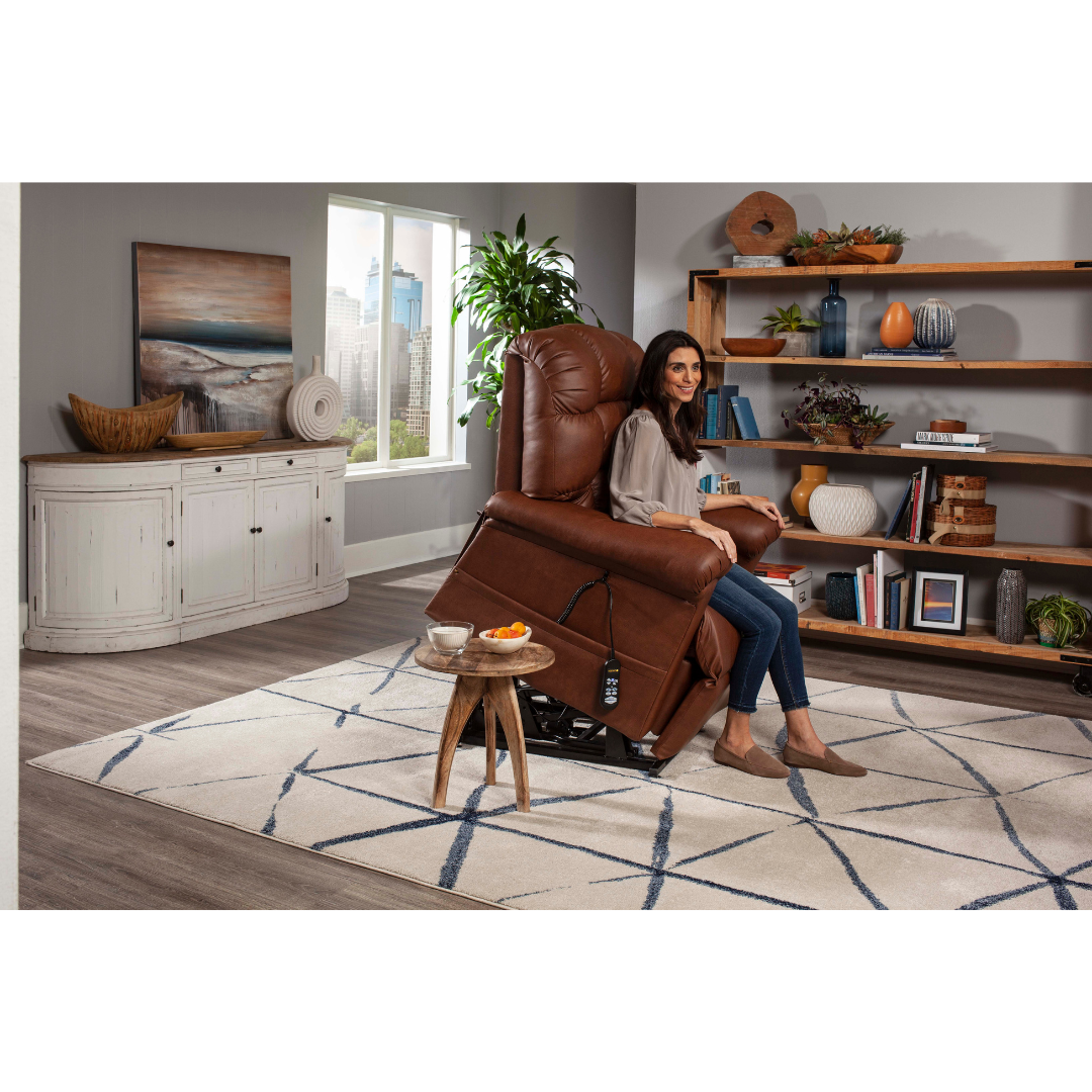 In a modern living room with a patterned rug, wooden shelf with decor, white sideboard, large window city view, and potted plant, a woman relaxes in ergonomic comfort on the Golden Tech PR515 Cloud Recliner With Lift Assist, ZG+ & Twilight - SM/MD.