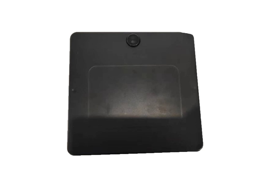 The ComfyGo Phoenix Carbon Fiber Electric Wheelchair boasts a sleek black square design with a carbon fiber texture. It features a slightly raised circular button at the top center, has a matte finish with a subtle rectangular indent, and contrasts elegantly against the plain white background.