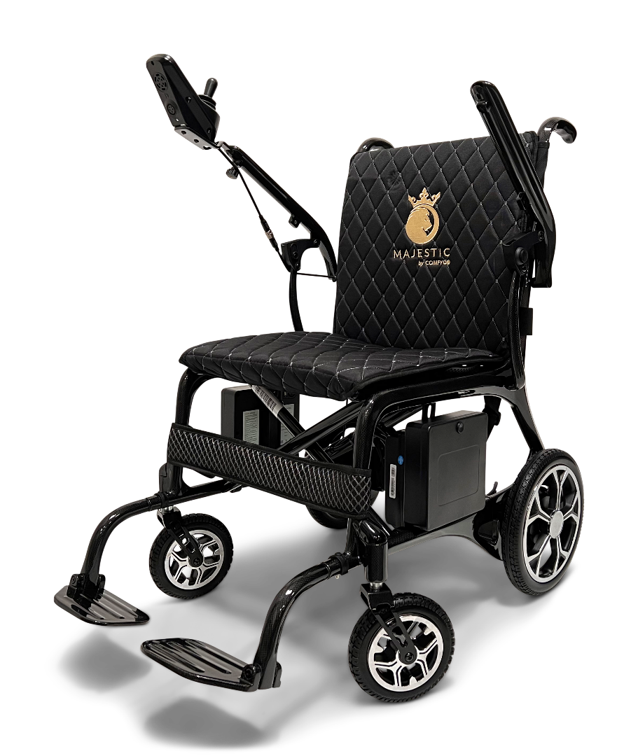 The ComfyGo Phoenix Carbon Fiber Electric Wheelchair offers a sleek, black design with a quilted seat cushion and foldable structure. It includes armrests, footrests, a control joystick, and features a backrest embroidered with Majestic in gold. Modern wheels sport metallic designs with carbon fiber accents.