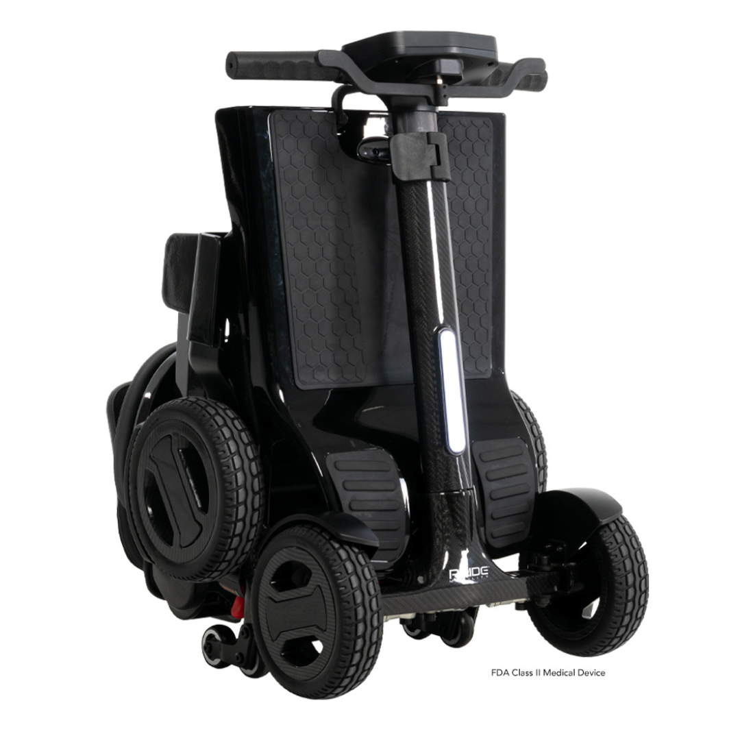 The Pride Mobility GoGo Carbon Ultralite Mobility Scooter, weighing only 35 lbs, is a compact, foldable black mobility aid with a sleek carbon fiber frame. It has smaller front wheels, larger rear wheels, a textured body finish, and handlebars with black grips for convenient transport and storage.