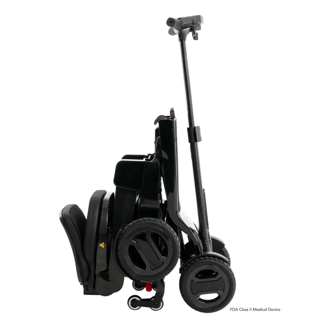 The Pride Mobility GoGo Carbon Ultralite Mobility Scooter, weighing only 35 lbs, is black and lightweight. It features a sleek carbon fiber frame with neatly folded seat and handlebars, two large wheels, and a small support wheel for easy transport.
