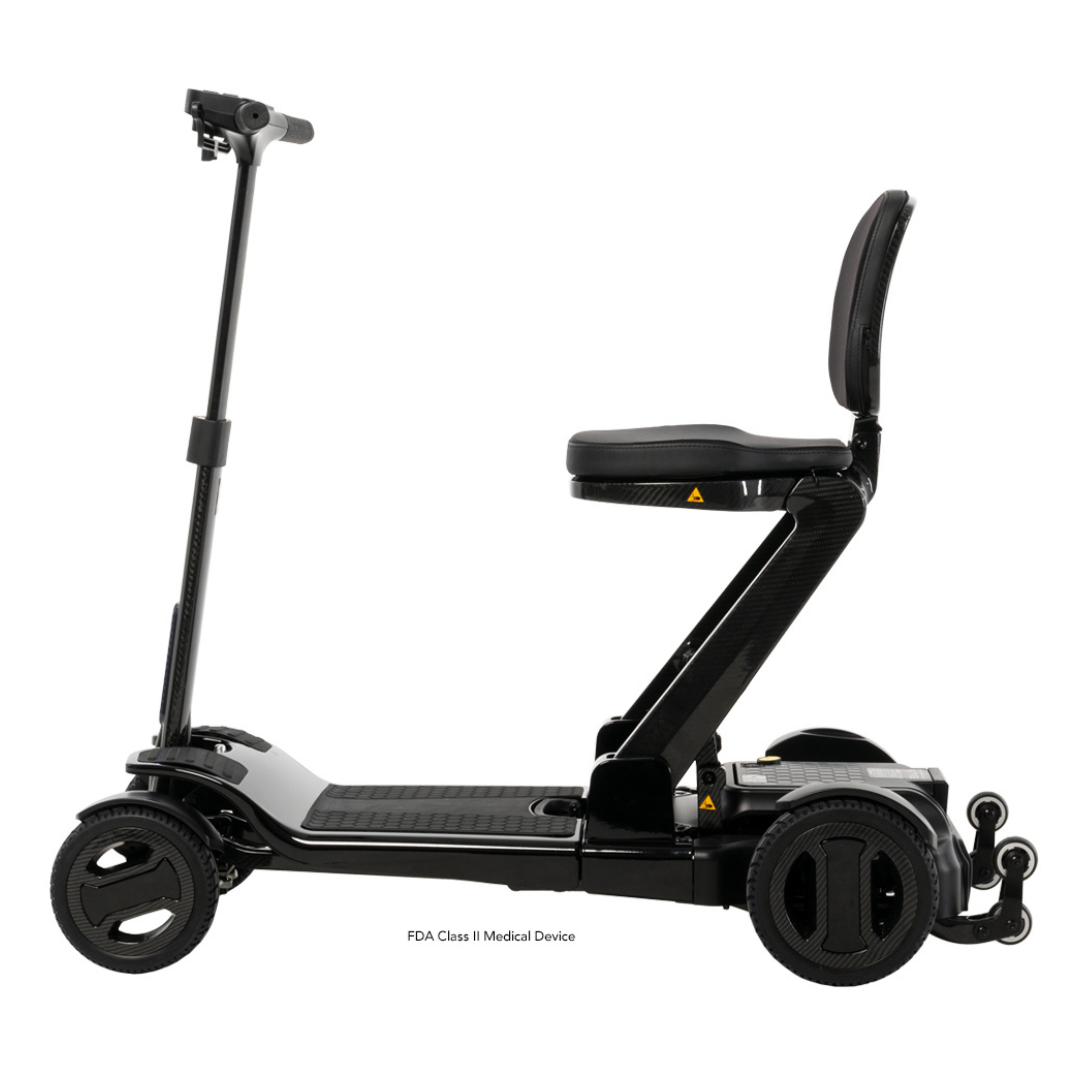 The Pride Mobility GoGo Carbon Ultralite Scooter, weighing just 35 lbs, is a black three-wheeled portable mobility solution with a carbon fiber frame. It features a foldable design, sleek-patterned wheels, and an elevated seat for comfort and enhanced maneuverability.