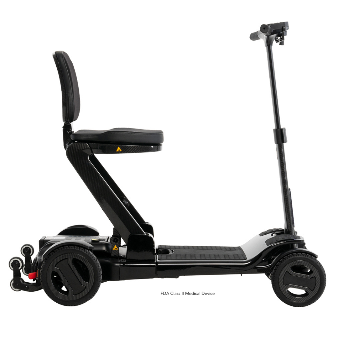 Side view of the Pride Mobility GoGo Carbon Ultralite Mobility Scooter, a black foldable electric model with four wheels and a seat. This 35 lbs lightweight scooter features adjustable handlebars and a padded seat for comfort, with a durable carbon fiber frame for easy transport.