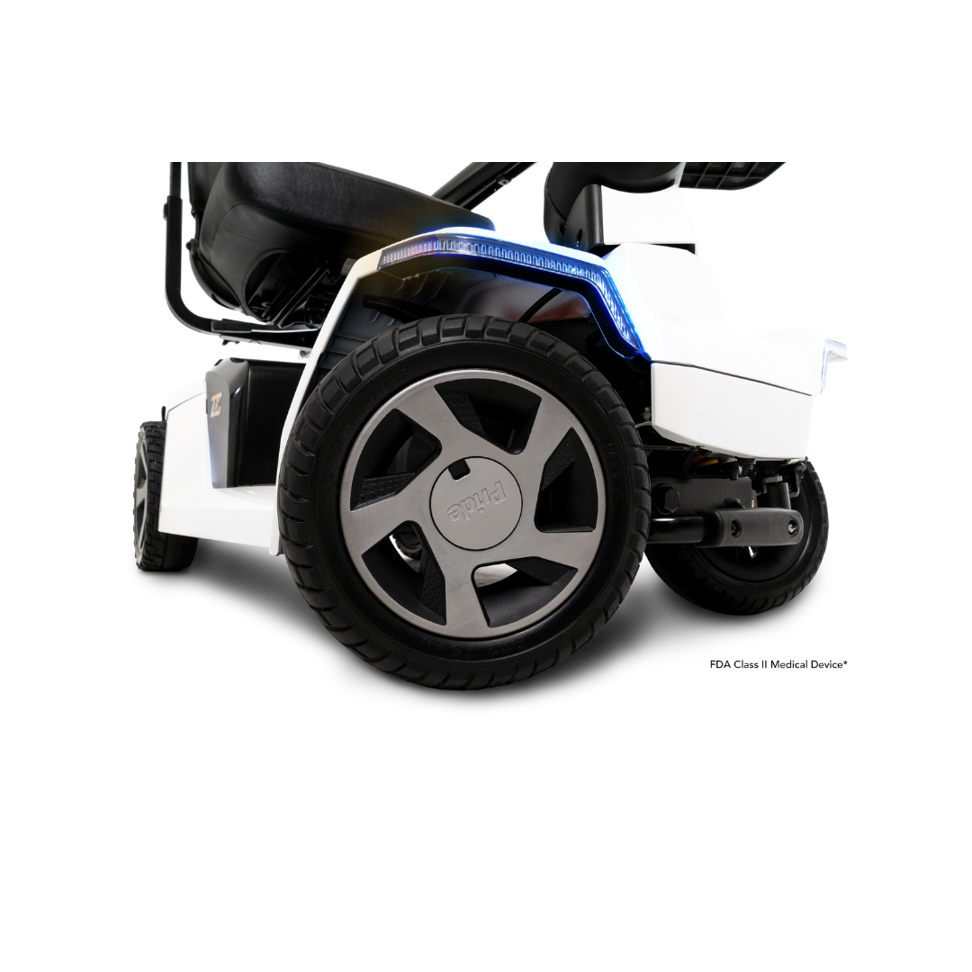 Close-up view of the rear wheel and lower body of the white Pride Mobility Zero Turn 10 HD Scooter, featuring a black tire, seat, blue accent light above the wheel, and innovative EZ Turn Technology for smooth maneuverability.