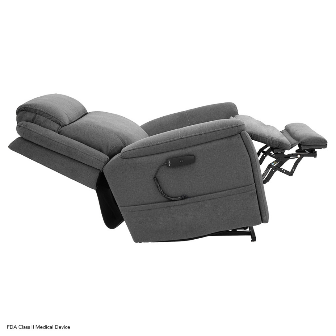 The Pride Mobility Evolution Collection Power Lift Recliner features plush gray upholstery, a fully extended footrest, tilted headrest, and an attached remote control for premium comfort and convenience.