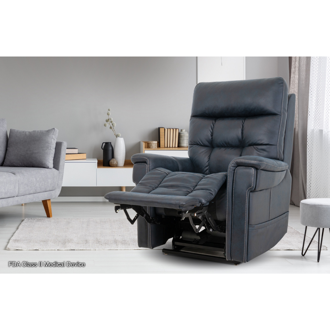 The Pride Mobility VivaLift! Radiance Recliner with Lift Assist & Heat, in dark gray with extended footrest and infinite positioning, is set in a modern living room alongside a light sofa, low white cabinet, vases, and neutral-colored curtains.