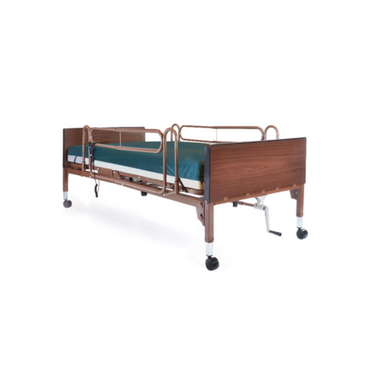 A hospital bed with wooden headboard and footboard, ProBasics Reduced Gap Full-Length Bed Rail for safety, thin green-covered mattress, and wheels on each leg, shown against a plain white background.