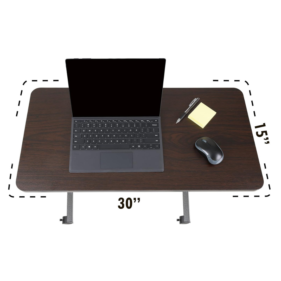The Roscoe Rolling Overbed Table - Non-Tilting Bedside Table is a rectangular dark wood rolling laptop desk (30 x 15) shown with a laptop, pen, sticky notes, and a wireless mouse on top.