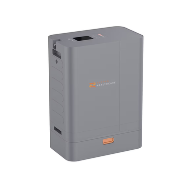 The Rhythm Oxygen Concentrator Premium Bundle is a compact, rectangular gray device featuring a small display screen, top buttons, CAIRE Healthcare logo on the front, handle slot, and an orange button near the base.