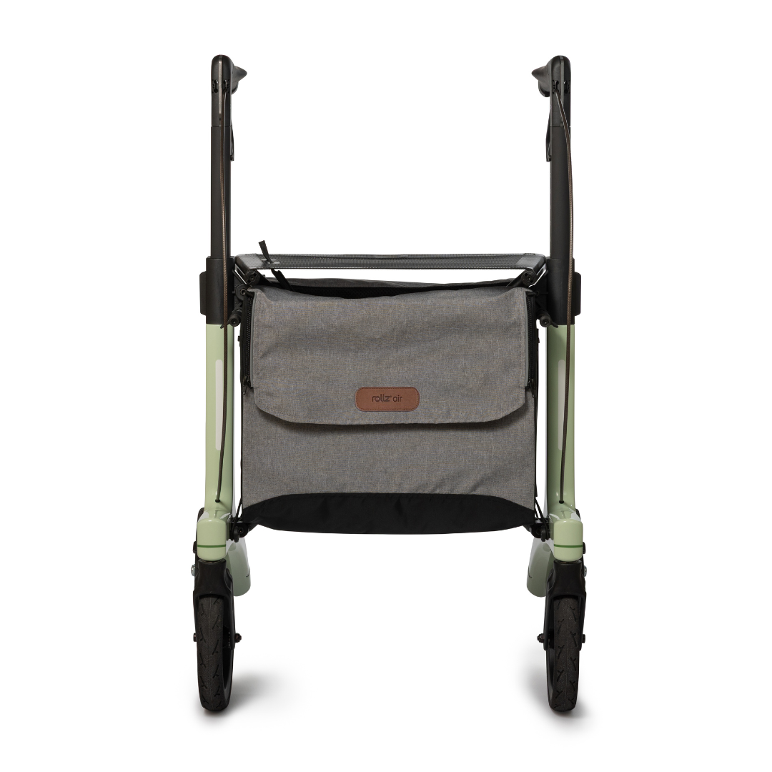A front view of the Rollz Air Lightweight Folding Carbon Rollator (10.4 lbs) with a gray storage bag between the light green and black handles. The bag features a leather logo patch.