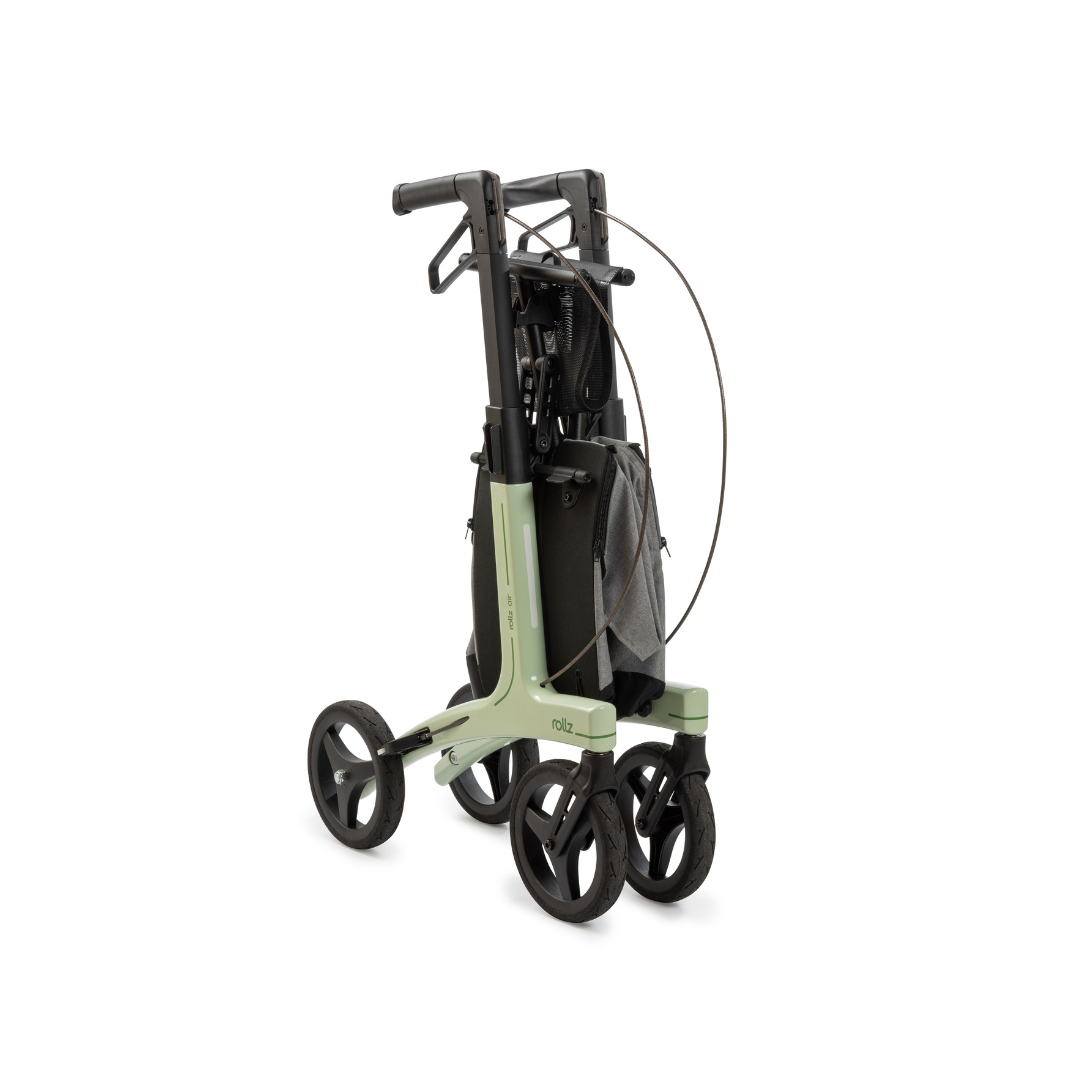 The Rollz Air Lightweight Folding Carbon Rollator, weighing just 10.4 lbs, features a green frame, four large wheels, and a gray storage pouch, shown folded compactly for easy storage and transport.