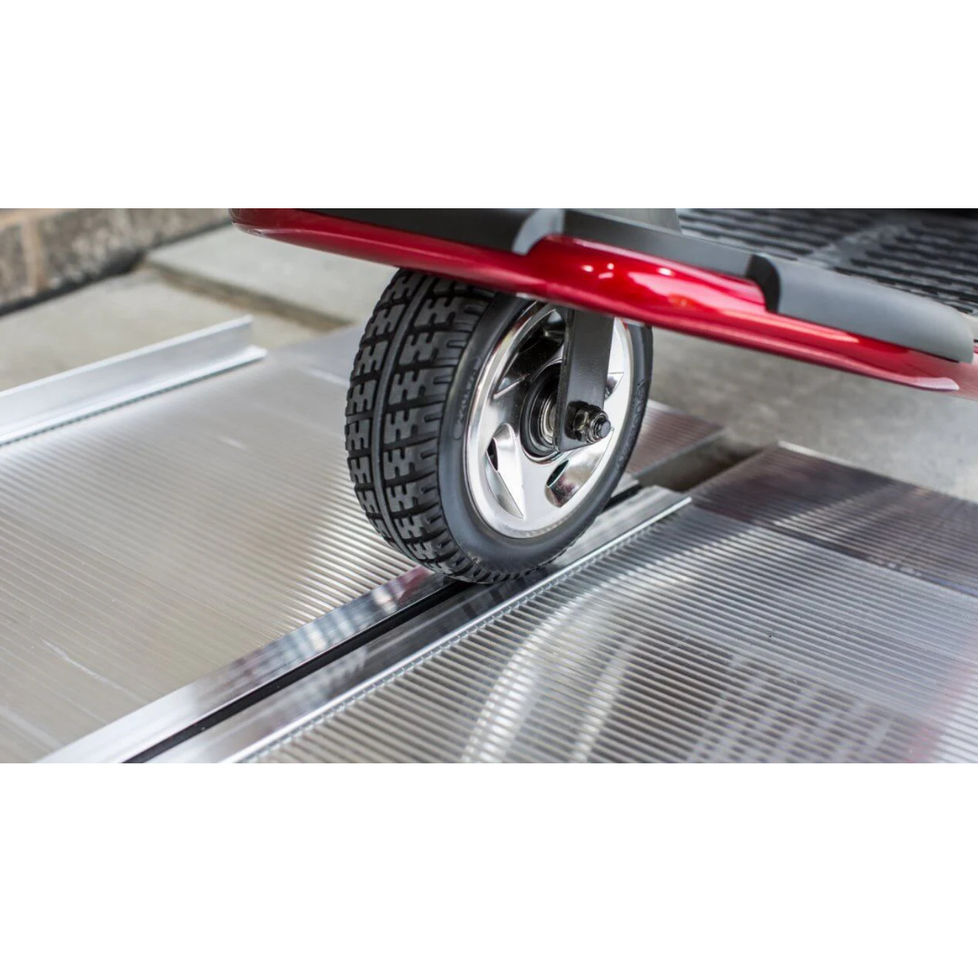 Close-up of the EZ-Access SUITCASE® Singlefold Mobility Ramp—Portable, with a mobility scooter wheel crossing its ridged metal surface for smooth transitions over steps. View specs, warranty info, or watch videos to learn more.