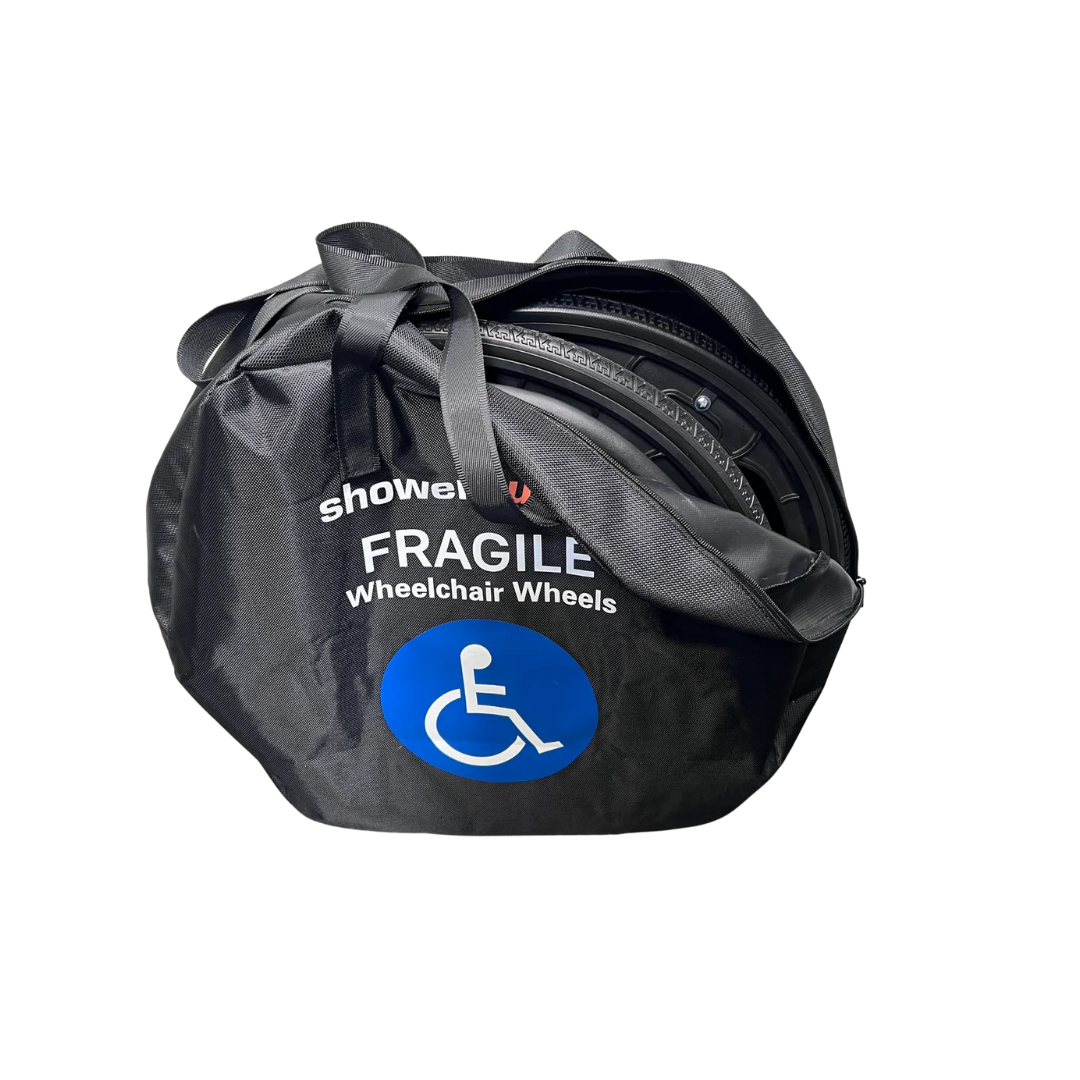 A black handled bag labeled "Fragile Wheelchair Wheels" with a blue wheelchair symbol holds a pair of shower wheelchair wheels—perfect for users of the ShowerBuddy Solo Traveller - Portable Shower Wheelchair.