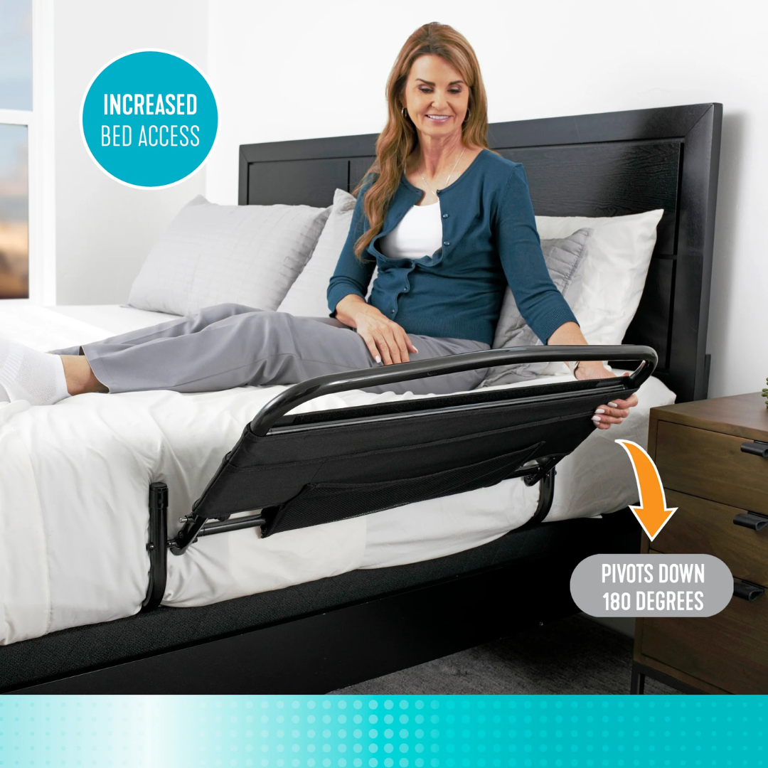 A woman lifts the Stander Safety Bed Rail & Padded Pouch (30" Rail) attached to her bed; an arrow illustrates its 180-degree pivot for easy access and fall protection. A nightstand sits next to the bed.