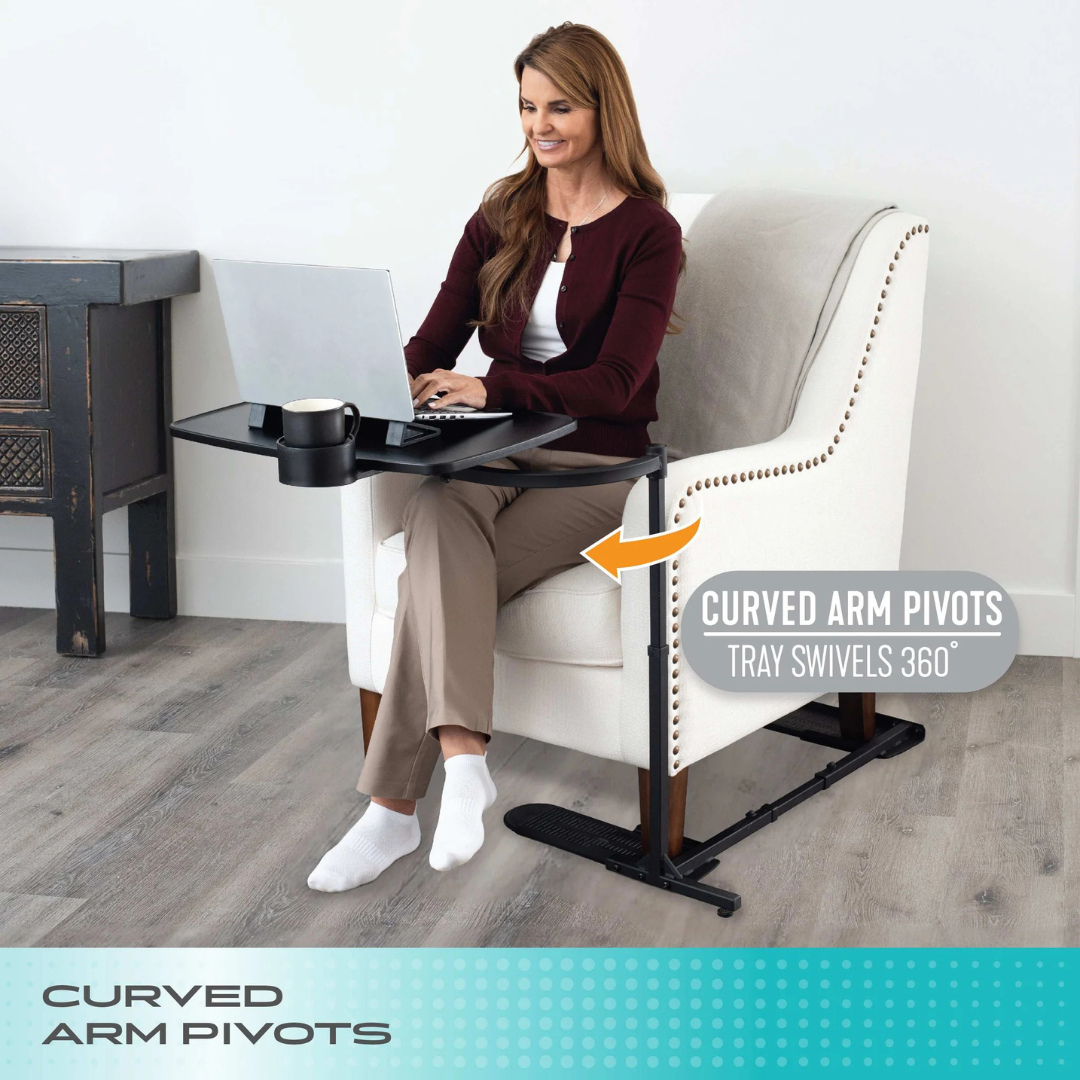 A woman sits in a white armchair using the Stander Wonder Tray XL, a black lap desk with an adjustable tray. An arrow highlights its curved arm pivots, showing the tray swivels 360° for versatile living room use.