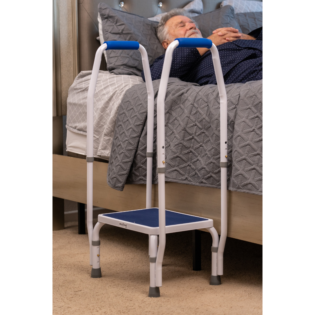 A man lies on a bed with the Step2Bed Mini Bedside Stepper, featuring handrails, positioned beside him to assist with fall prevention and safe bed entry and exit.