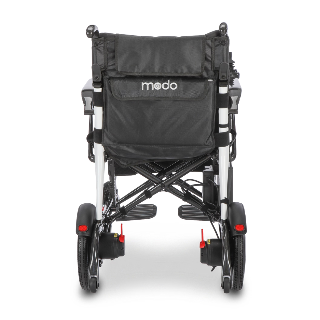 A black Whill MODO Breeze Ultra-Lightweight CF Folding Electric Wheelchair viewed from the back, highlighting its rear wheels, footrests, and a storage pocket on the backrest.